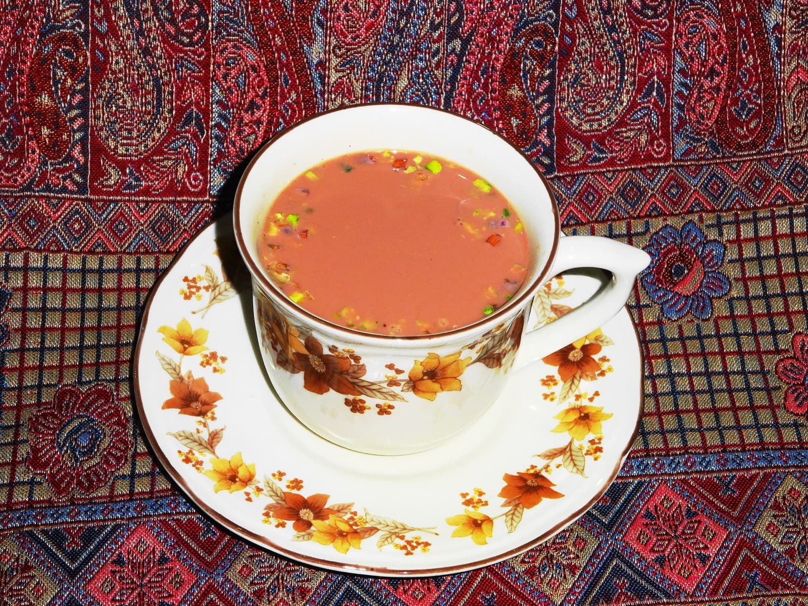 A cup of pink Kashmiri chai on a patterned cloth