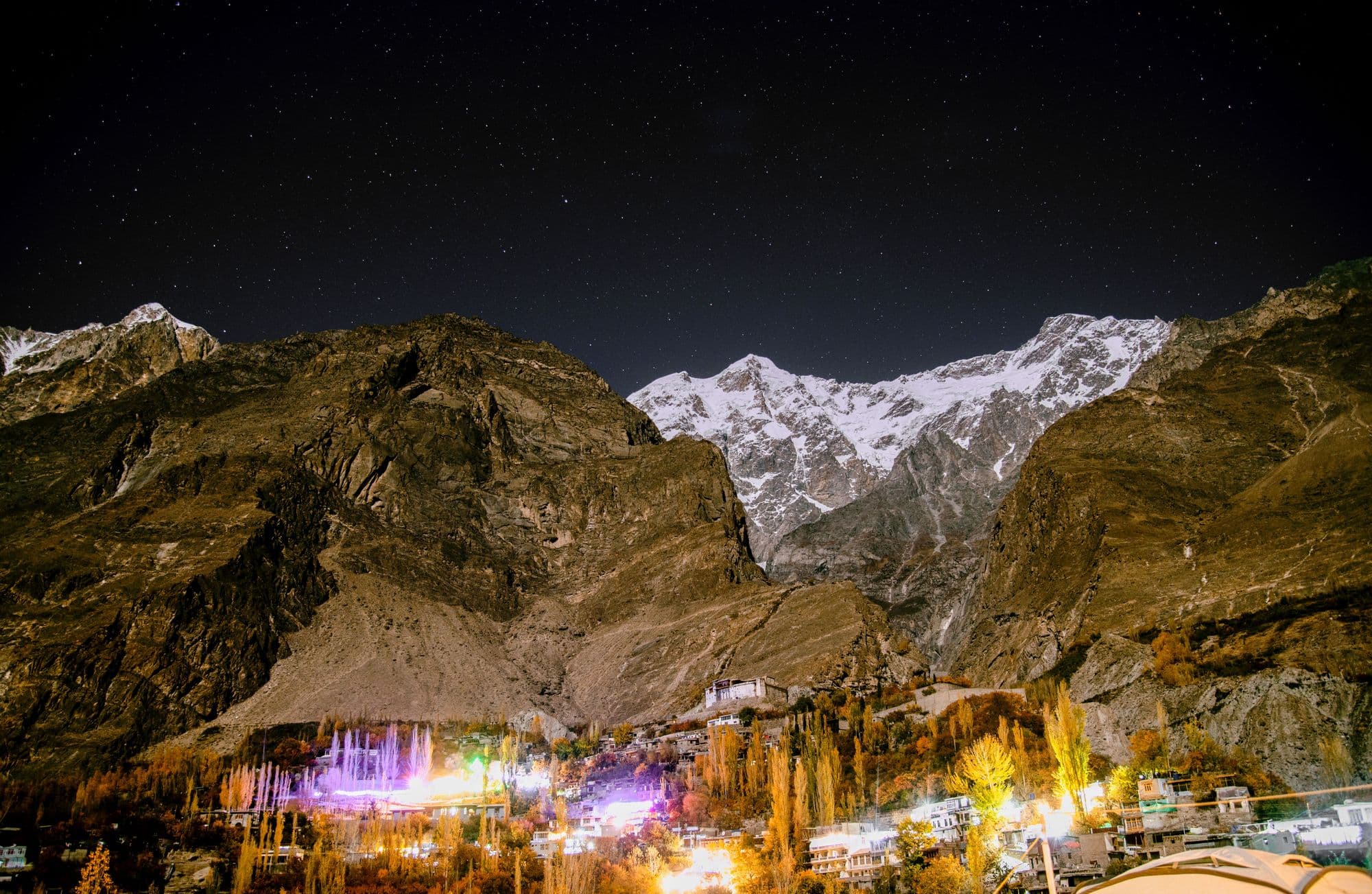 Lights of Karimabad village scattered across the Hunza hillside under a starry sky
