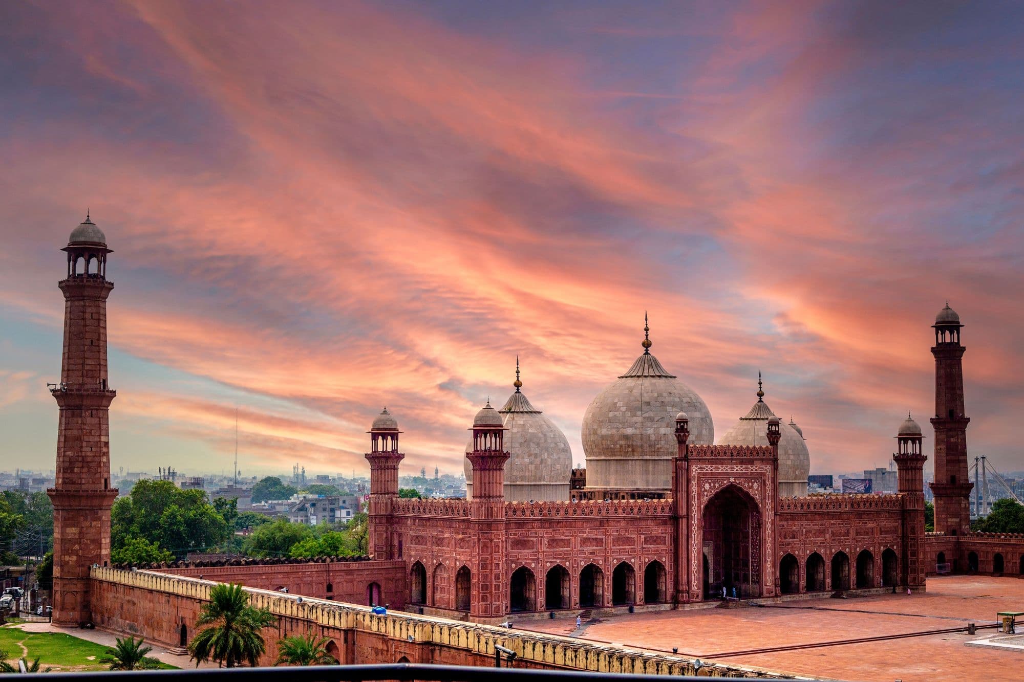 Red-sandstone domes and minarets of Badshahi Mosque, Lahore, under a sunset sky